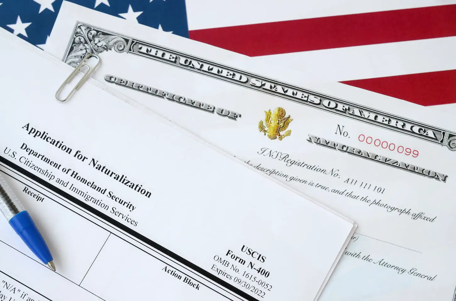 An image of N-400 Application for Naturalization and Certificate of naturalization lies on United States flag.