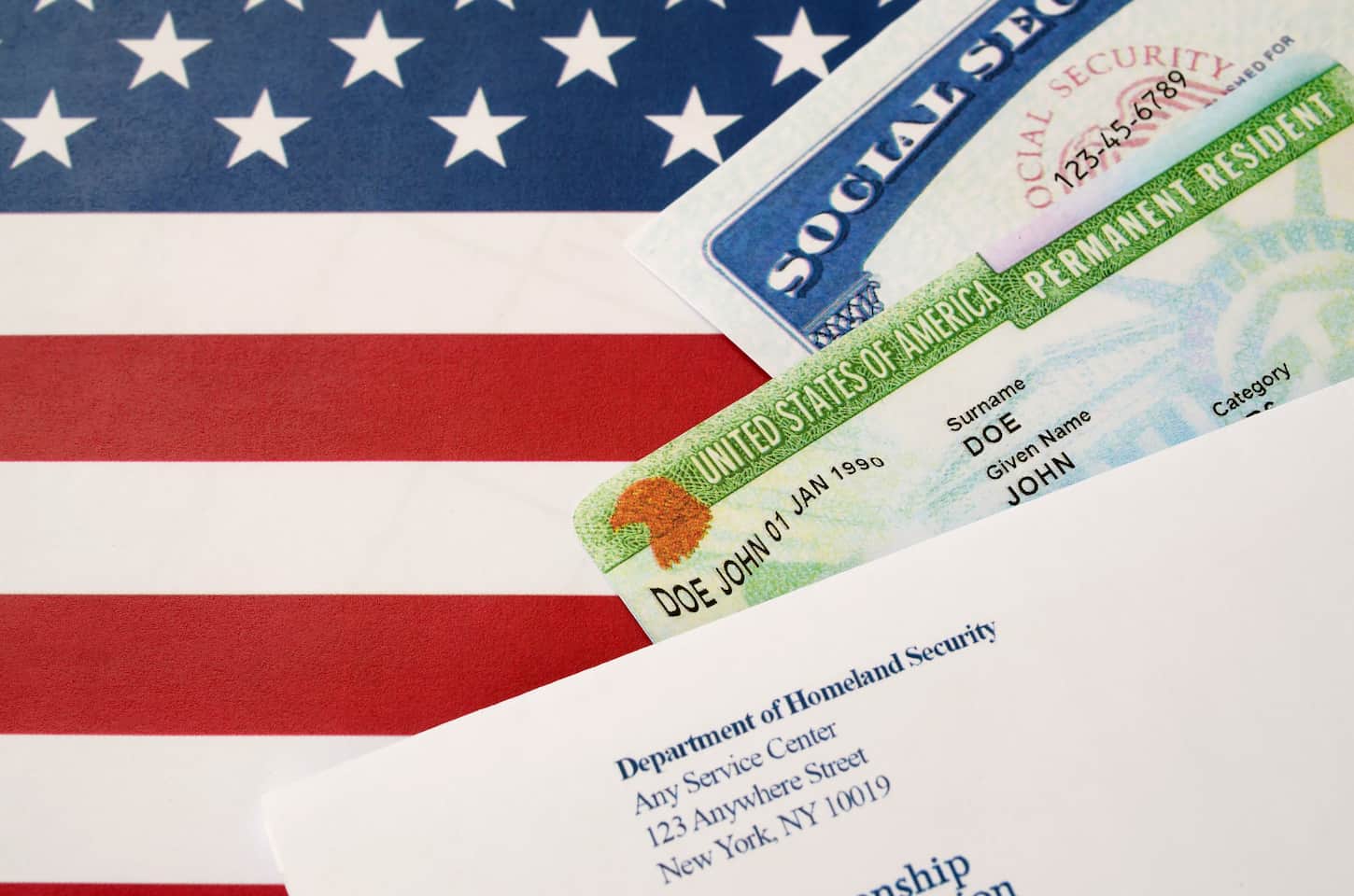An image of a United States permanent resident green card from DV-lottery with social security number lies with USCIS envelope on the US flag close up.