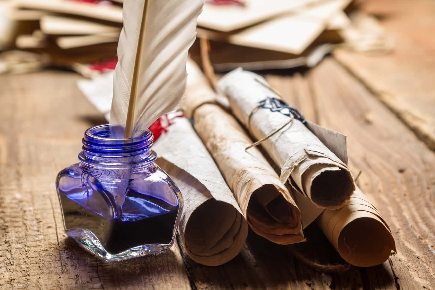 An image of old scrolls and blue ink in the inkwell.