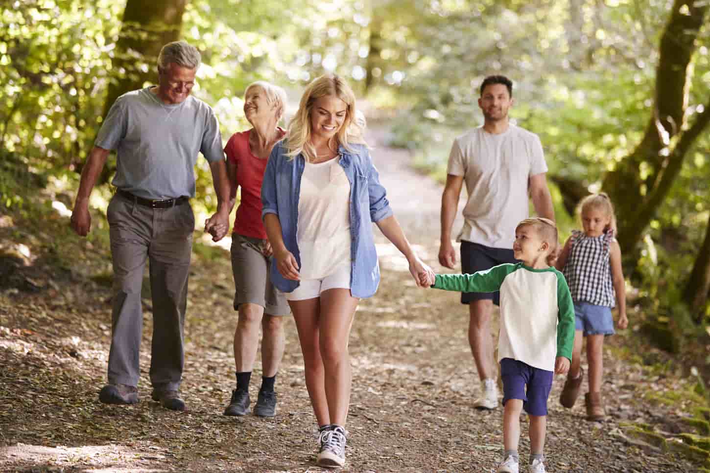 An image of a Multi-Generation Family Enjoying Walk Along Woodland Path Together.