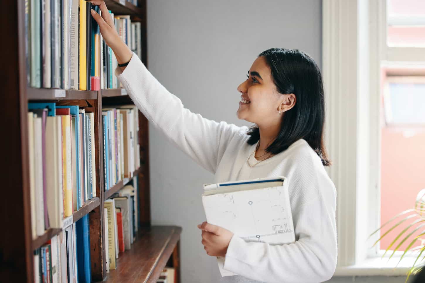 An image of a young woman reading a book in her school library.